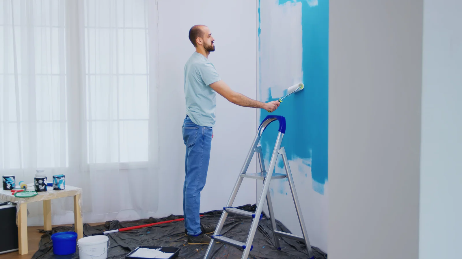handyman-painting-wall-with-roller-brush-dipped-white-paint-handyman-renovating-apartment-redecoration-home-construction-while-renovating-improving-repair-decorating-scaled